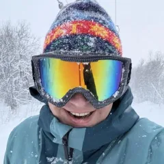 Daniel in ski goggles and a striped hat, in the snow